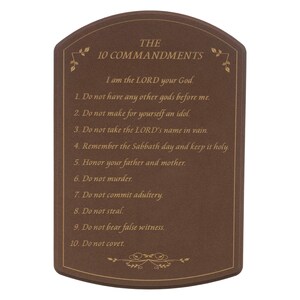 May include: A brown plaque with rounded edges displays "THE 10 COMMANDMENTS" in gold lettering. The text of the commandments is also in gold. Decorative floral accents are at the top and bottom of the plaque.