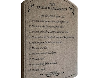 May include: A rectangular, arched-top plaque with the text "THE 10 COMMANDMENTS" and the Ten Commandments. The plaque is a light gray color with black text and decorative flourishes.