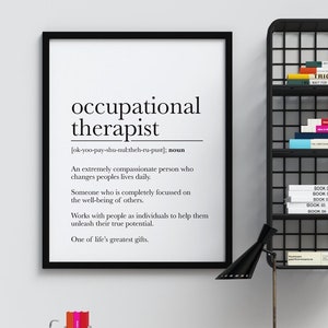 Puede incluir: Una impresión enmarcada en blanco y negro con la definición de "terapeuta ocupacional" sobre un fondo blanco. La impresión está colgada en una pared blanca sobre un escritorio de madera con una lámpara de metal negro, un sujetalibros de bicicleta de metal y un conjunto de tres cajones con frentes negros, blancos y verdes. Los cajones están etiquetados con los números 1, 2 y 3.