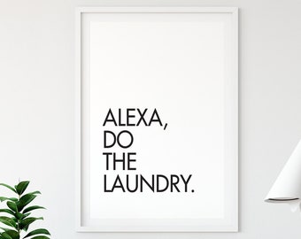 May include: A white framed print with black text that reads "ALEXA, DO THE LAUNDRY." The print is hanging on a white wall with a wooden chair and a white lamp in the background.