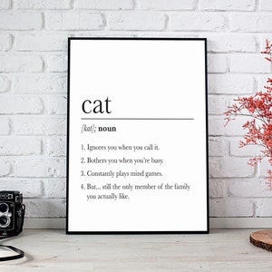 Peut inclure: Une impression murale d'art imprimable en noir et blanc avec la définition du mot "chat" dans un style dictionnaire. La définition se lit comme suit : "[kat] ; nom 1. Vous ignore lorsque vous l'appelez. 2. Vous dérange lorsque vous êtes occupé. 3. Joue constamment à des jeux d'esprit. 4. Mais... reste le seul membre de la famille que vous aimez vraiment."