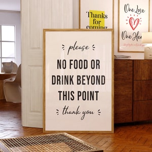 Könnte beinhalten: Ein weißes Schild mit schwarzem Text, auf dem steht "please NO FOOD OR DRINK BEYOND THIS POINT thank you". Das Schild ist in Holz gerahmt und hängt an einer Wand.