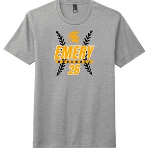 May include: A gray t-shirt with the word "EMERY" in yellow and white, with a baseball graphic. Below the word "EMERY" is the word "BASEBALL" in yellow. The number "26" is below the word "BASEBALL" in yellow.