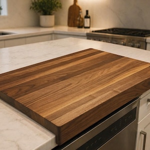 May include: A rectangular, solid wood chopping board in a deep brown hue. The board has a smooth, polished finish and visible wood grain. The chopping board is positioned on a white countertop in a kitchen.