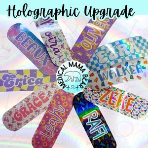 May include: A collection of ten colorful holographic bandages with names printed on them. The names include Beau, Moira, Oliver, Ezra, Walker, Erica, Grace, Leah, Zeke, and Rafi.