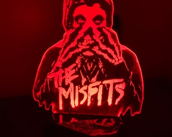 May include: Red illuminated 3D printed lamp featuring a silhouette of a person with their hands covering their face. The text "The Misfits" is printed below the silhouette.