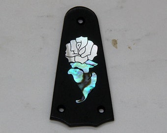 May include: A black guitar pick with a white and iridescent abalone inlay of a rose.