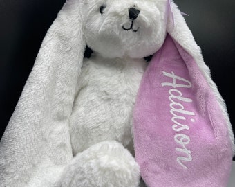 May include: White plush bunny with long floppy ears. One ear is pink and embroidered with the name "Addison". The bunny has purple bows on its head.