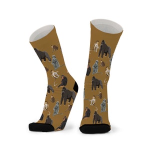 May include: A pair of brown socks with a pattern of gorillas and monkeys. The socks are on a white background.