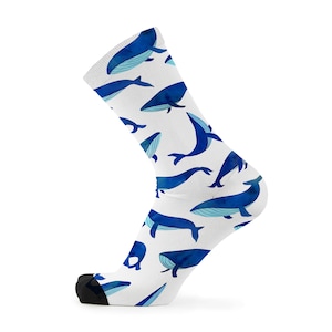May include: White socks with a blue whale pattern. The whales are in various sizes and positions, some swimming, some jumping. The socks are a fun and whimsical way to add a touch of personality to any outfit.