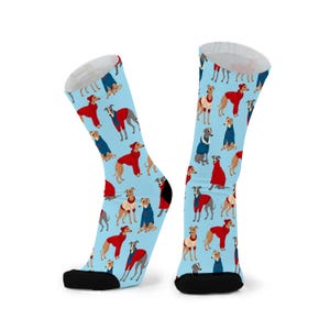 May include: A pair of light blue socks featuring a repeating pattern of greyhounds in different coloured coats. The socks have black heels and toes, and white tops.