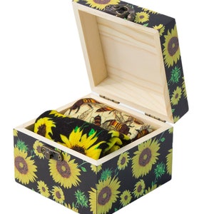 May include: A wooden box with a sunflower print design. The box is open and contains two pairs of socks with sunflower and bee patterns.