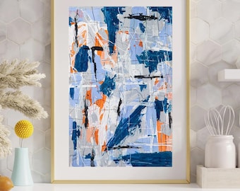 May include: Abstract art print in a gold frame. The artwork features a mix of blue, orange, grey, and black brushstrokes on a light blue background. The painting is displayed on a white surface with a light blue cabinet.