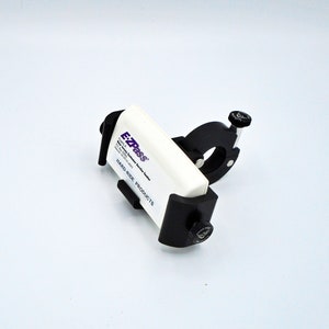 May include: A black and white EZ Pass transponder holder with the text "EZ Pass" and "Hard-Ride Products" on the white transponder. The holder has a black knob on the side.