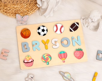 May include: A wooden puzzle with colorful pieces shaped like letters, sports balls, and other objects. The puzzle is personalized with the name "BRYSON".