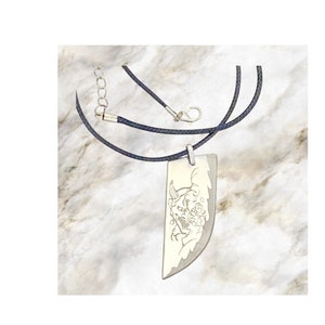 May include: A silver-colored pendant necklace with a black cord. The pendant is rectangular with a curved edge and features an engraved design of a demon-like face. The necklace has a silver clasp and adjustable chain.