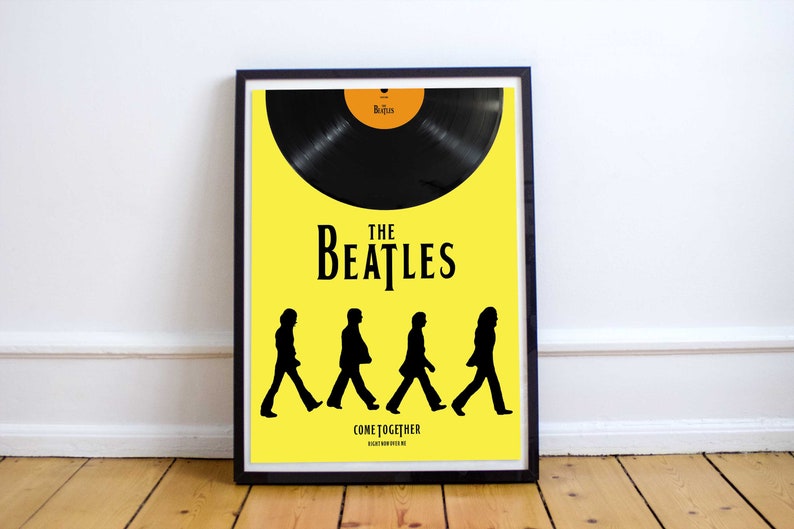 Puede incluir: Un p&oacute;ster amarillo con un disco de vinilo negro en la mitad superior. La mitad inferior presenta una silueta negra de los Beatles caminando por el p&oacute;ster. El texto "The Beatles" est&aacute; en negro y el texto "Come Together" est&aacute; en letras negras m&aacute;s peque&ntilde;as.