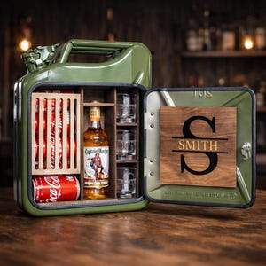 May include: A green metal jerry can repurposed as a mini bar. It contains Coca-Cola cans, a bottle of Captain Morgan Spiced Gold, shot glasses, and a wooden plaque with the name "SMITH" and a large initial. The bar is open, displaying its contents.