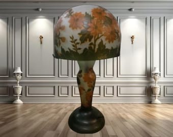 May include: A table lamp with a white and orange floral patterned glass shade and a matching base.