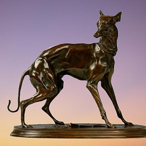 May include: A bronze sculpture of a greyhound dog standing on a wooden base. The dog is in a running pose with its head turned to the side. The sculpture is a classic example of animal art.
