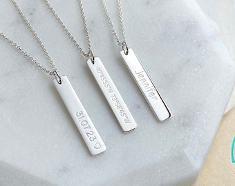May include: Three silver necklaces with personalized bar pendants. The pendants are engraved with the text "Jennifer", "31.07.23", and "40.45'55" N 73.58'45" W".