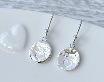 Pendientes colgantes de plata de ley martillada con forma de disco y detalle de corazón. Pequeños y delicados, de 10 mm.