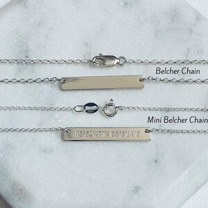 Puede incluir: Dos collares plateados con colgantes de barra y cadenas finas. El collar superior est&aacute; etiquetado como "Belcher Chain". El collar inferior, etiquetado como "Mini Belcher Chain", tiene coordenadas grabadas. Ambos collares tienen cierres.