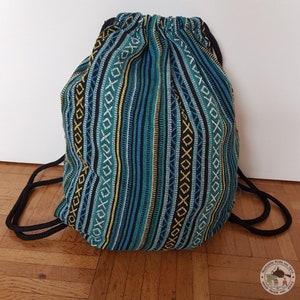 Pode incluir: Uma bolsa de cordão azul, preta e amarela com cordões pretos. A bolsa é feita de um tecido tecido com um padrão geométrico.