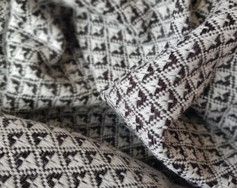 Puede incluir: Primer plano de una tela con estampado blanco y negro con un diseño en forma de diamante. La tela es suave y texturizada, y parece estar tejida.