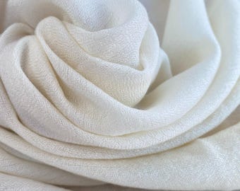 May include: A close-up of a white fabric scarf, showing the soft, drapey texture and subtle sheen.