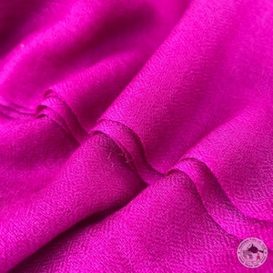 May include: Close-up of a bright pink fabric with a soft, smooth texture. The fabric is folded in a way that shows the subtle sheen of the material.