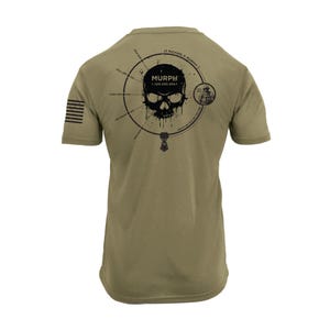 May include: Olive green t-shirt with a black graphic of a skull and the word "MURPH". The design includes a circular diagram with text and a small illustration. The shirt also features a US flag on the sleeve.