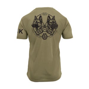 May include: Olive green t-shirt featuring a graphic of two German Shepherds, one with a muzzle, inside a circular design. The text "MILITARY WORKING DOG HANDLER" and "K9 31K" are also visible.