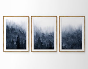 May include: Three framed prints of a watercolor painting of a foggy forest in shades of blue. The prints are arranged in a row on a white wall.
