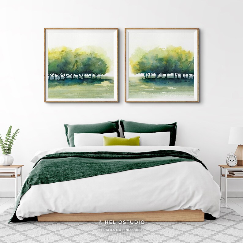 Pode incluir: Duas pinturas de aquarela emolduradas que representam uma fileira de &aacute;rvores em um campo verde. As pinturas est&atilde;o penduradas em uma parede branca acima de uma cama com roupa de cama verde.