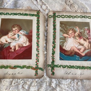 May include: Two vintage Christmas cards with green holly borders. The cards feature illustrations of children with their pets. The first card shows a girl holding a white cat and the text "Amy and Pet". The second card shows a girl holding a dog and the text "Edith and Gift".