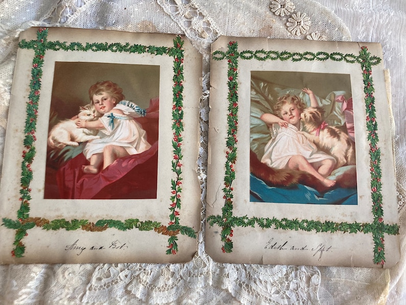 May include: Two vintage Christmas cards with green holly borders. The cards feature illustrations of children with their pets. The first card shows a girl holding a white cat and the text "Amy and Pet". The second card shows a girl holding a dog and the text "Edith and Gift".