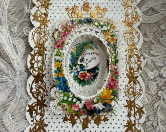 Puede incluir: Una tarjeta vintage blanca con un borde dorado y un diseño floral. La tarjeta tiene un óvalo recortado en el centro con un diseño floral y la palabra "Friendship" escrita en cursiva.