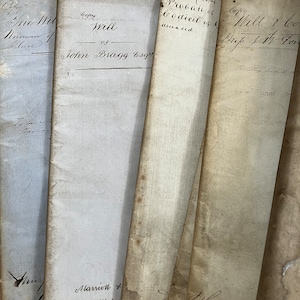 Puede incluir: Primer plano de varias páginas viejas, amarillentas y descoloridas de un libro. Las páginas están llenas de texto escrito a mano con tinta negra. El texto incluye las palabras "Copy Will of John Bragg Esq" y "Probate of Codicil of deceased."