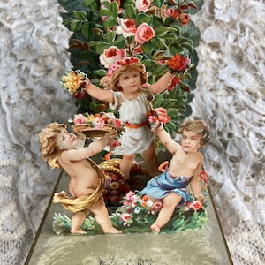 Hermosa tarjeta 3D mecánica alemana del siglo XIX, niños entre flores