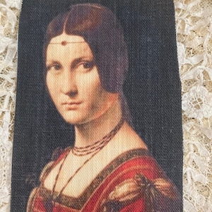Peut inclure: Portrait d'une femme aux cheveux foncés, vêtue d'une robe rouge et or avec un collier de perles. L'arrière-plan est sombre.