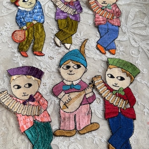 May include: Embroidered fabric appliques featuring whimsical figures in various outfits. The figures have stylized faces and are dressed in colorful jackets, pants, and hats. Some figures hold musical instruments, while others hold a tennis racket.