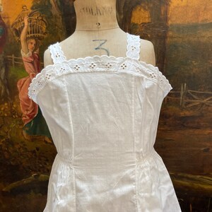 May include: White cotton slip dress with a lace trim and a gathered skirt.