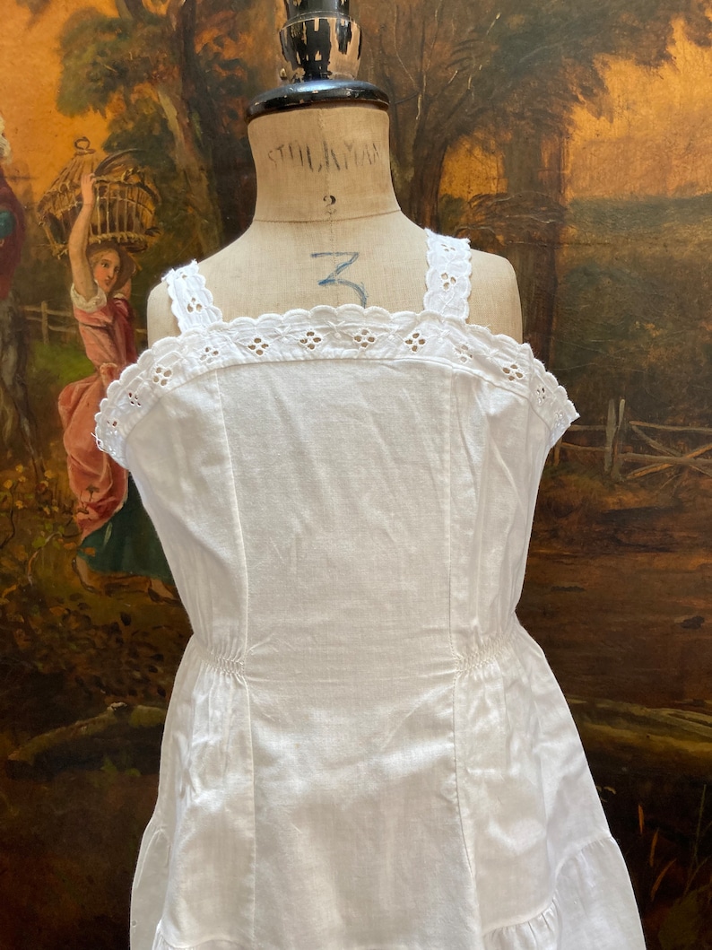 May include: White cotton slip dress with a lace trim and a gathered skirt.
