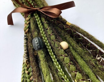 May include: A bundle of synthetic dreadlocks in shades of olive green and dark brown, tied with a brown satin ribbon. The set features braided strands, wrapped sections, a dark grey textured bead, a light wooden bead, and small gold metal cuffs.