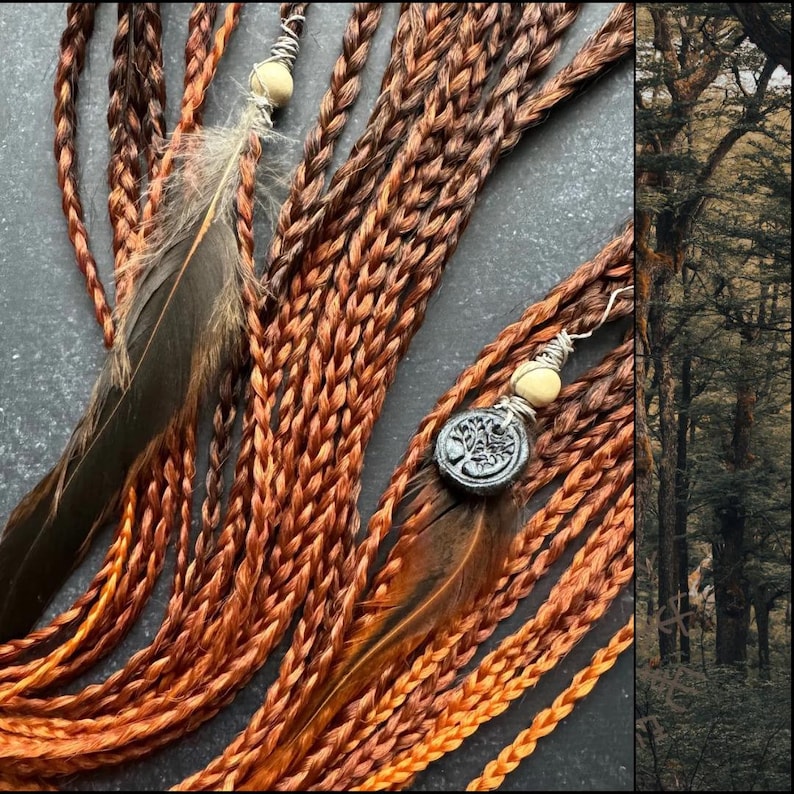 May include: A set of braided hair extensions in a warm copper color with brown highlights. The extensions are adorned with feathers and charms, including a tree of life pendant.