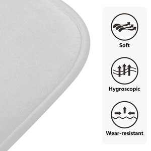 Puede incluir: Primer plano de una alfombra de ba&ntilde;o blanca, suave y absorbente con una superficie texturizada. La alfombra est&aacute; dise&ntilde;ada para ser c&oacute;moda, absorbente y resistente al desgaste.