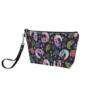May include: Black zippered makeup bag with a colorful skull and floral pattern. The bag has a black strap.