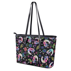May include: Black leather tote bag with a colorful sugar skull pattern. The skulls are decorated with flowers and paisley designs.