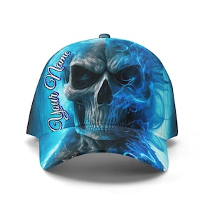 Może przedstawiać: Niebieska czapka z daszkiem z motywem czaszki i niebieskimi detalami płomieni. Czapka ma napis "Your Name" w ozdobnej czcionce. Wzór jest drukowany cyfrowo na czapce.